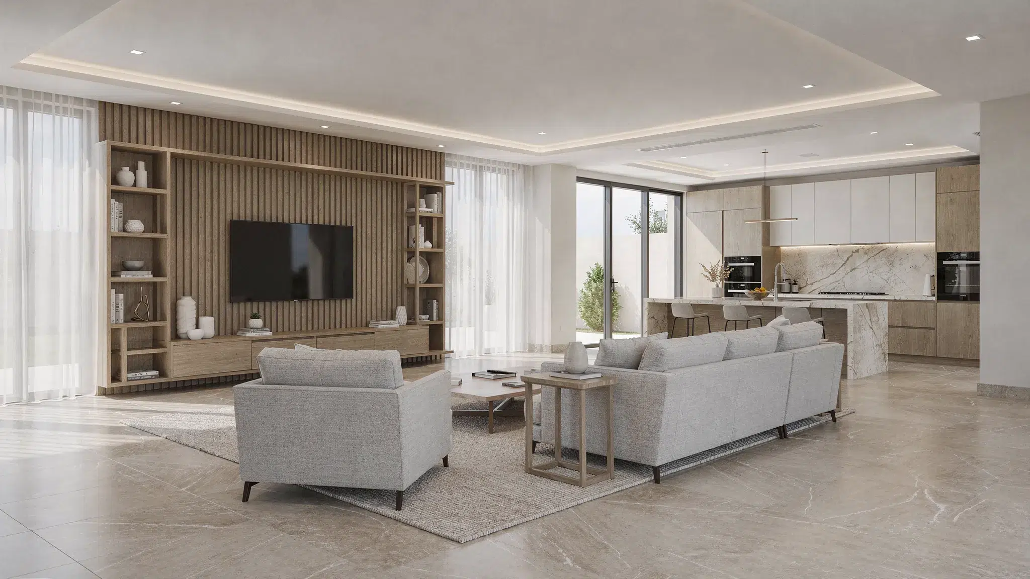 A renovated Dubai villa living room with modern neutral interiors, custom woodwork, stone-look floor tiles, recessed lighting and an open connection to a bright kitchen area.